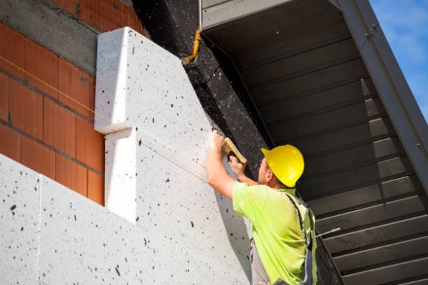 A construction worker insulates a building with styrofoam. Installation of polystyrene on the facade of the building. Building insulation